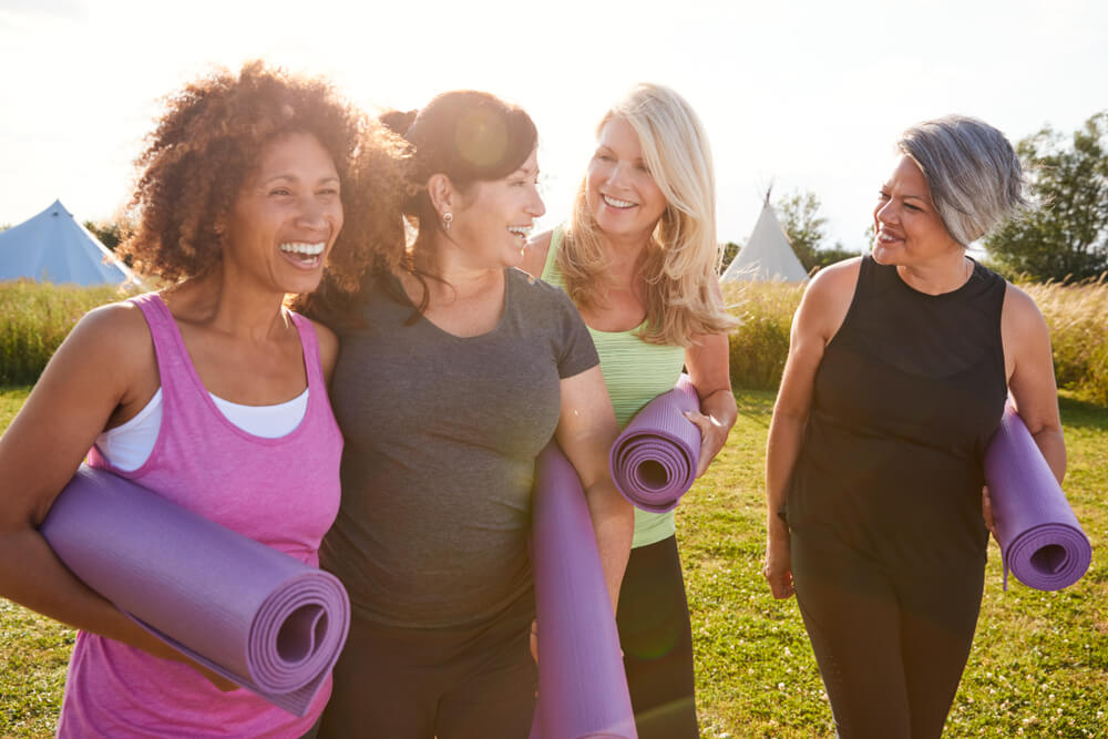 4 woman laughing and carrying yoga mats